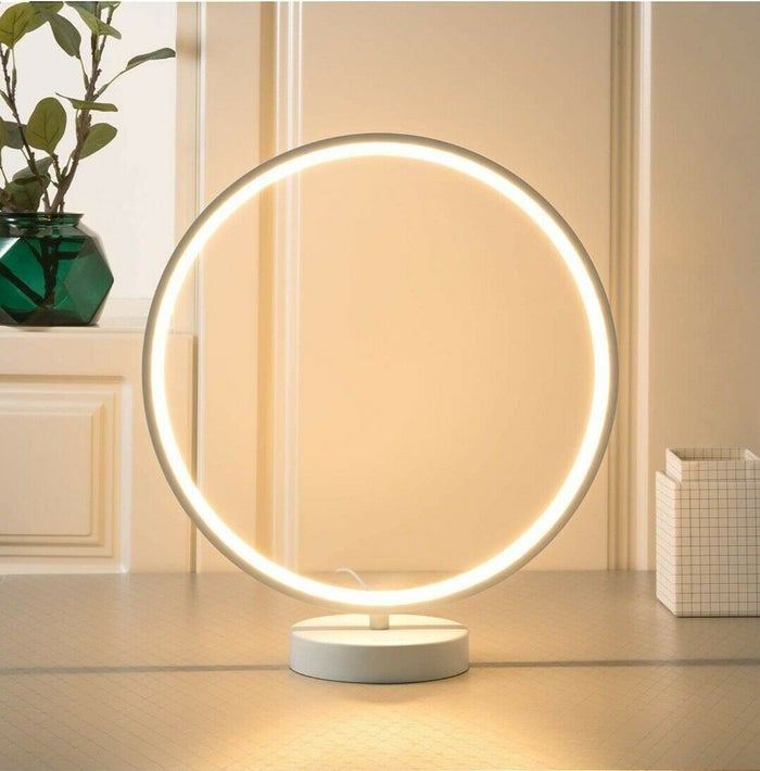 AUKEY Circular RGB Table Lamp is emitting yellow light on desk.